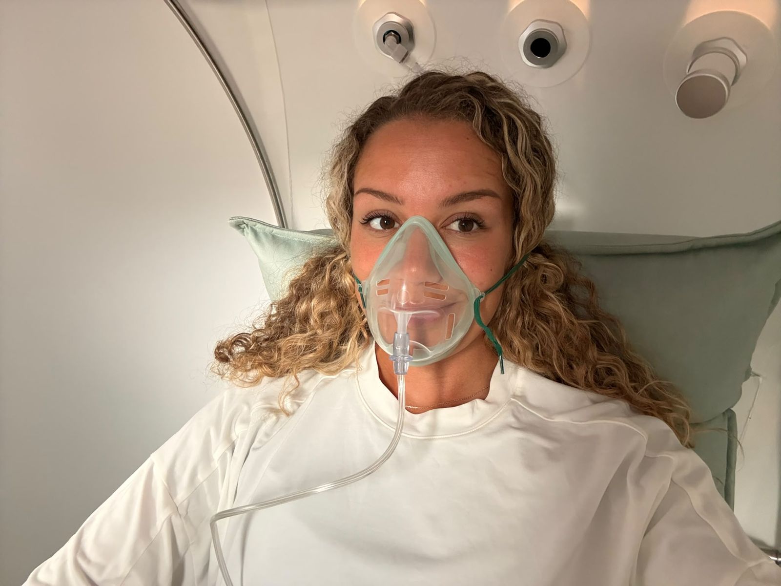 A client relaxing in the oxygen chamber with a soft mask